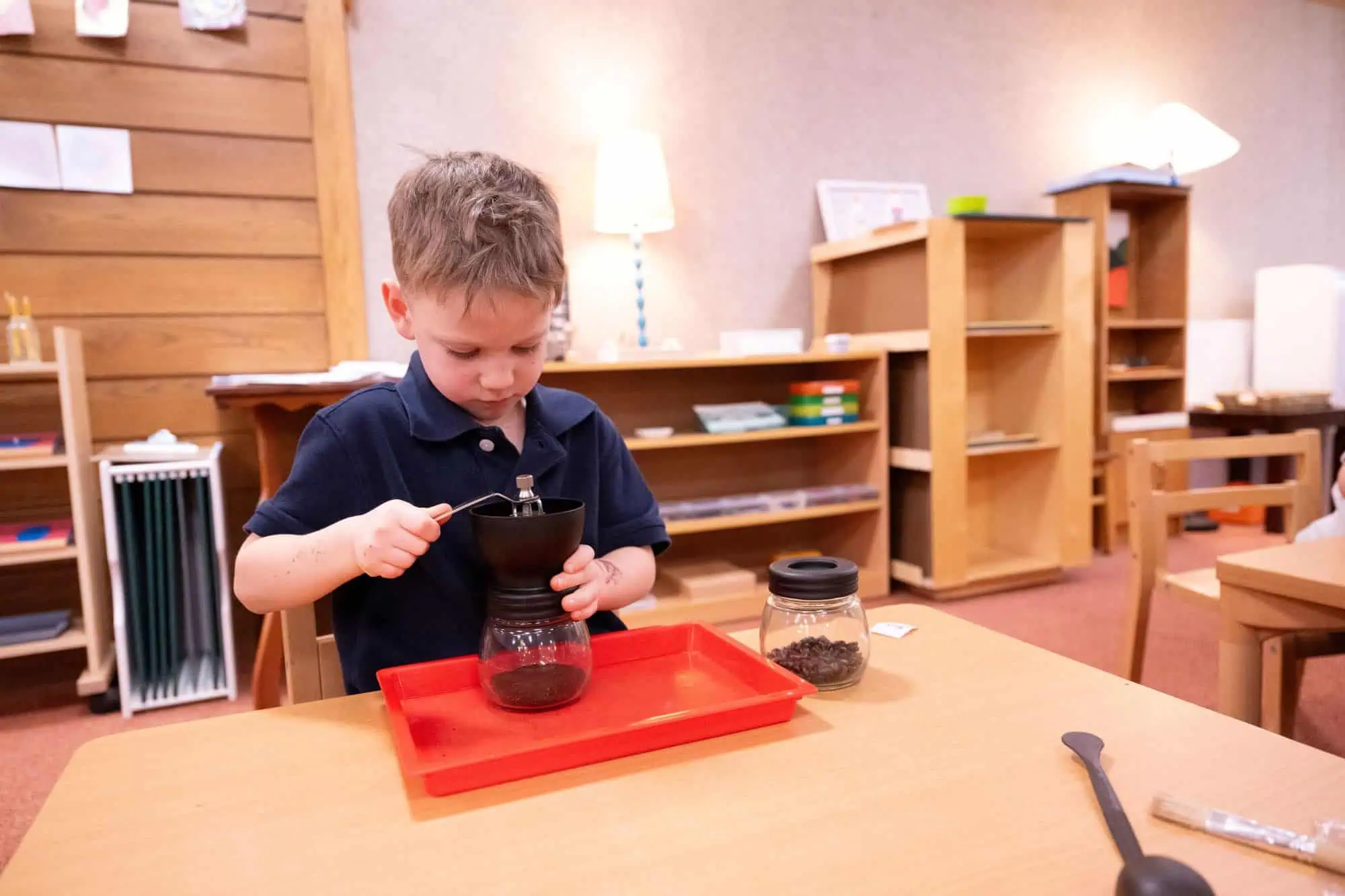 Casa Preschool Student learning practical life skills grinding coffee beans
