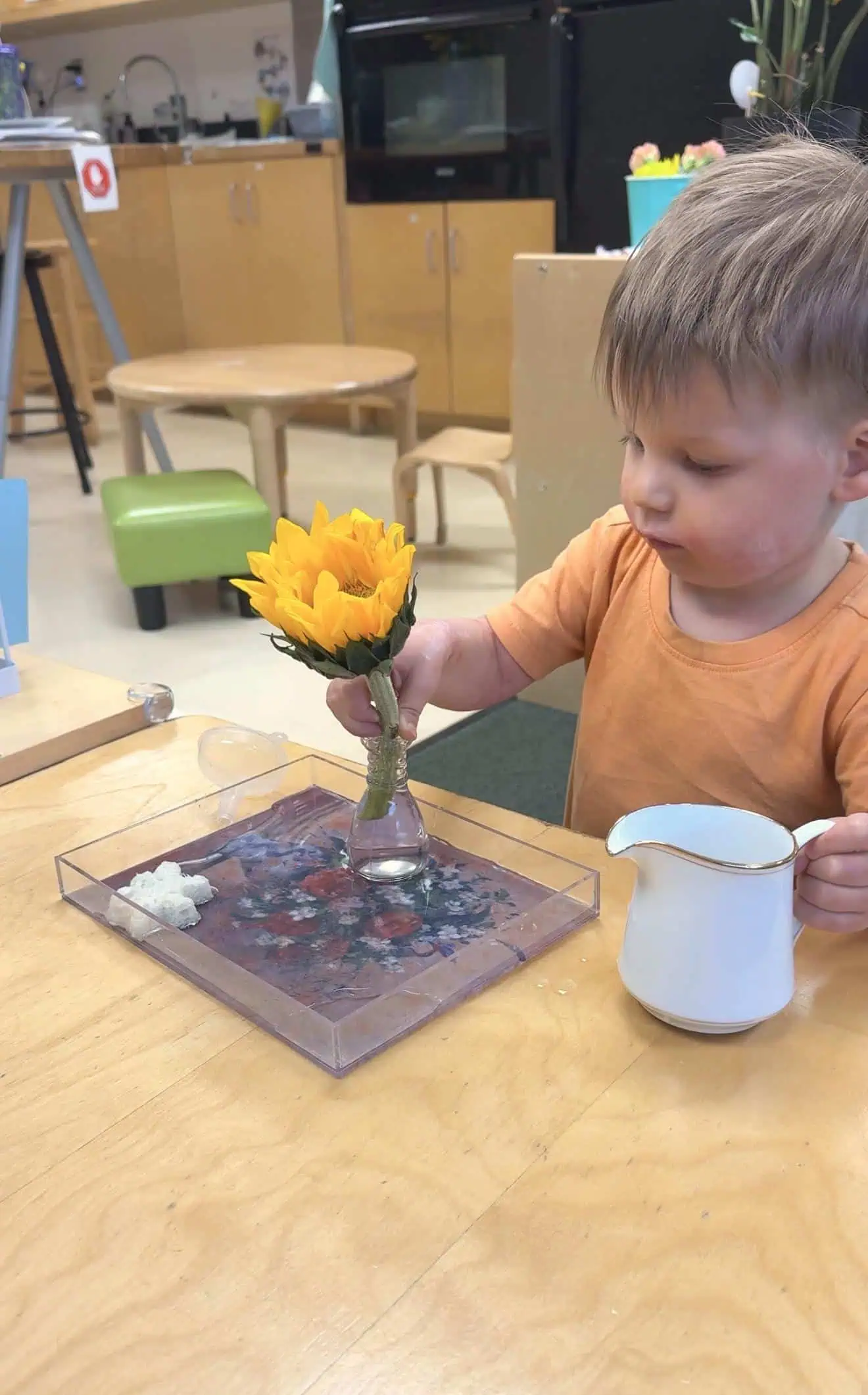 toddler putting a flower in a vase in a Christian Montessori childcare center