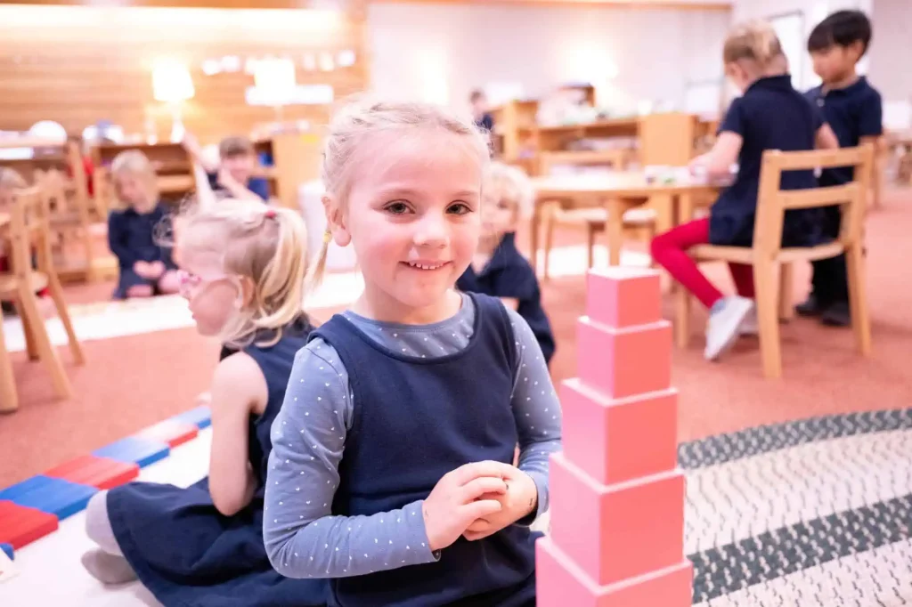 preschool student working with the pink tower, a Montessori sensorial material